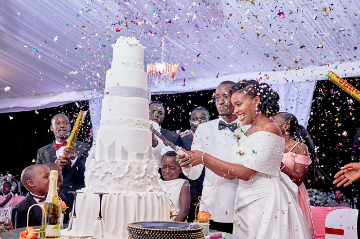 Bride cutting wedding cake with confetti celebration