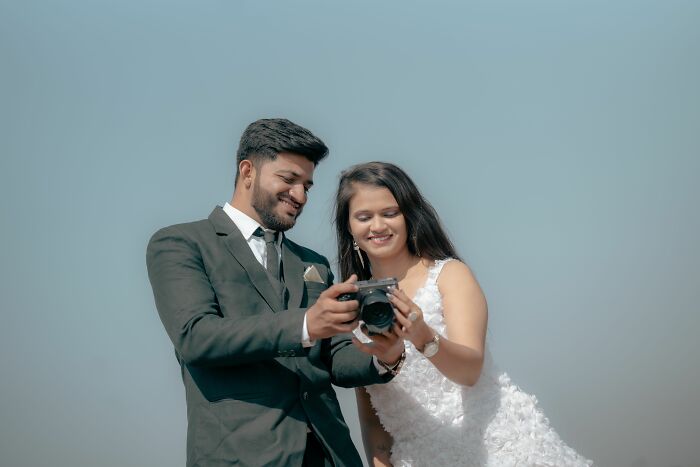 Bride and groom reviewing wedding photos on camera outdoors