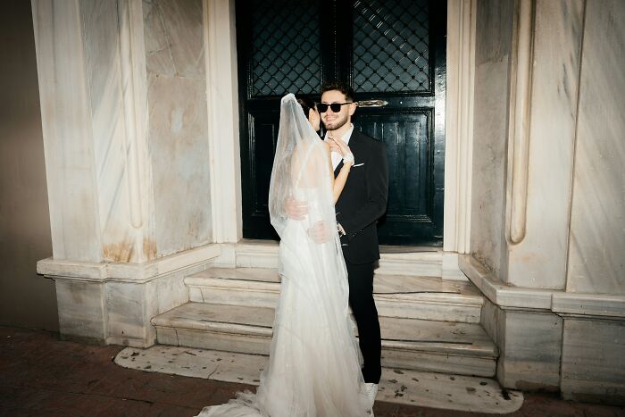 Bride and groom wearing sunglasses posing outside wedding venue