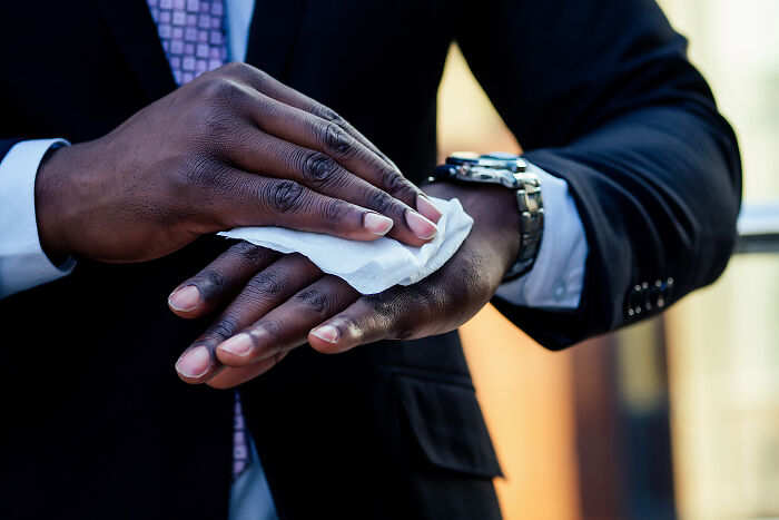 Man in suit cleaning hands with wipe showing hand hygiene