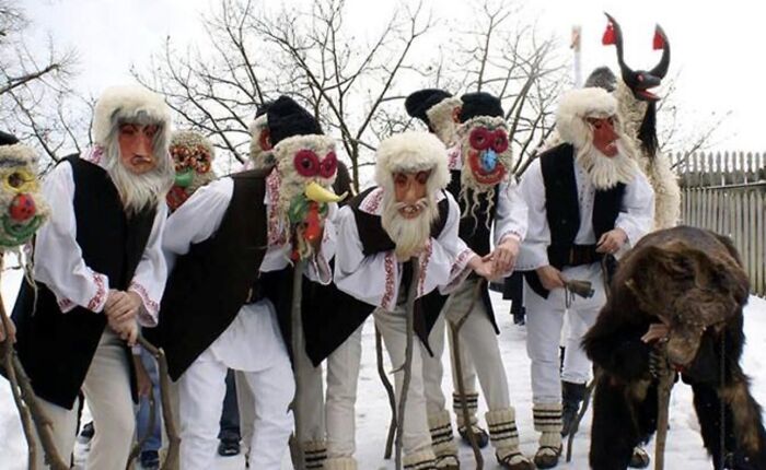 Group in traditional masks and costumes in snowy setting