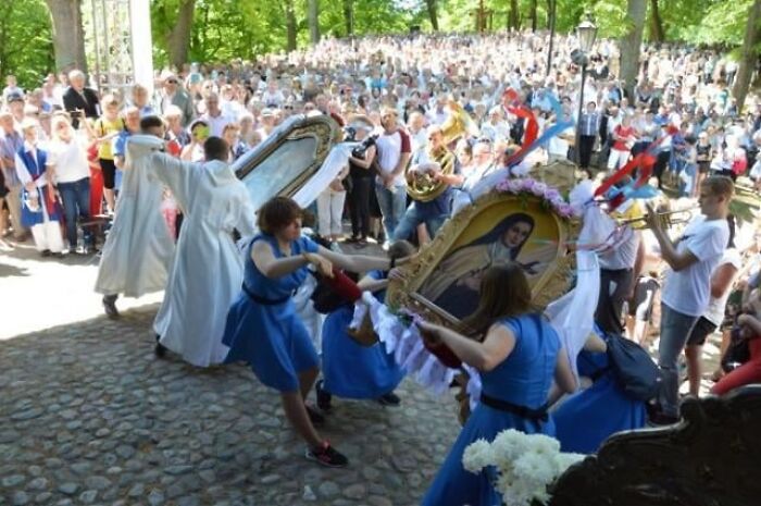 Crowd watching women swinging a religious icon in an outdoor local celebration