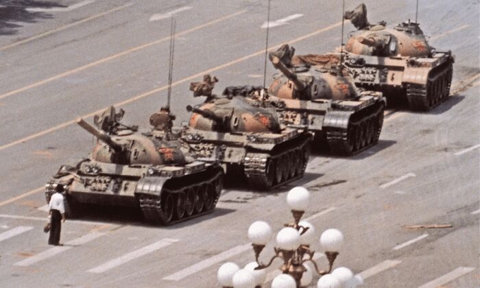 Man standing in front of line of military tanks on street