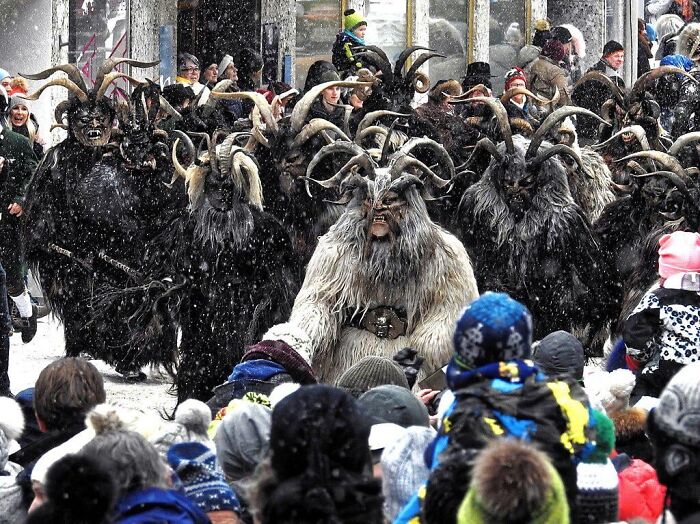 Krampus parade with people dressed in horned furry costumes during snowy weather