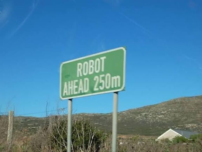 Green road sign warning of robot ahead in rural area