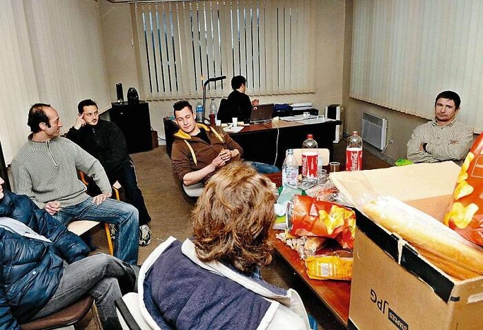 Casual indoor gathering with people sitting and chatting around a table with snacks