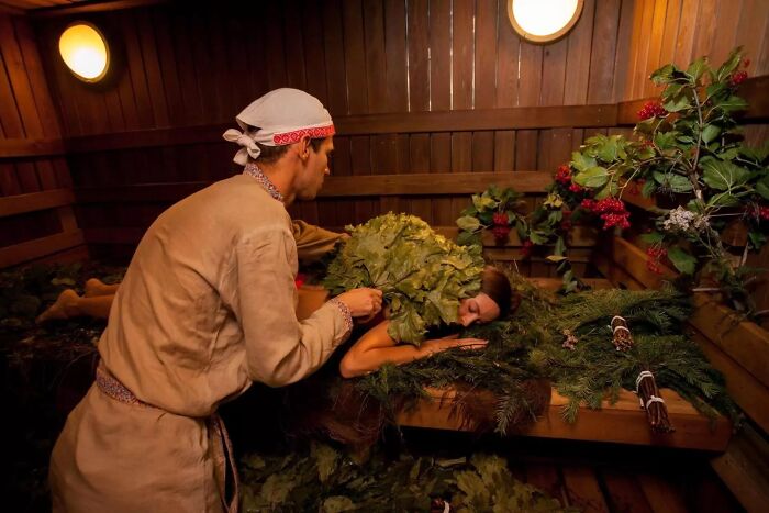 Traditional sauna massage using birch leaves in a wooden room