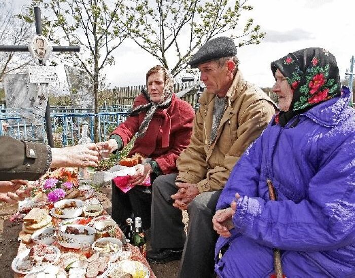 Eastern European people sharing food at a gravesite during a memorial
