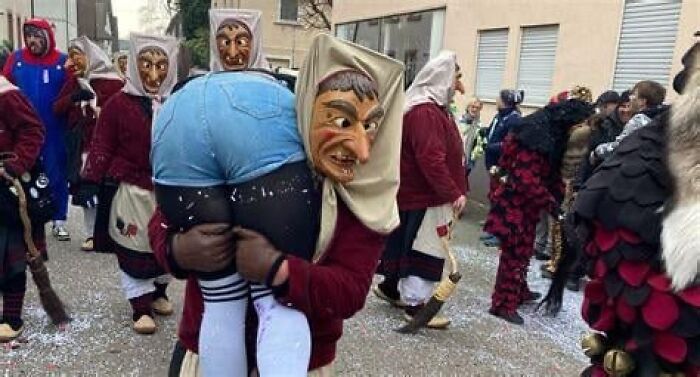 Festival participants wearing masks carrying person in unusual costume