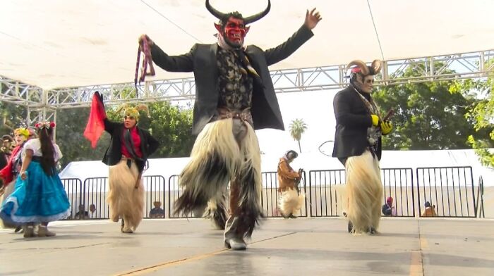 Traditional dance with performers wearing horned, furry leg costumes and masks
