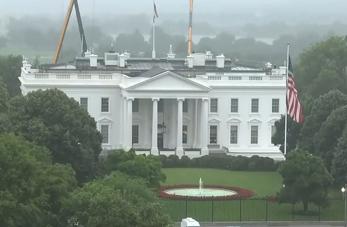 White House exterior with flag and fountain on a cloudy day