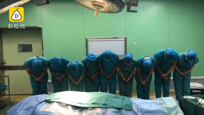 Medical team bowing together in operating room after successful surgery showing gratitude