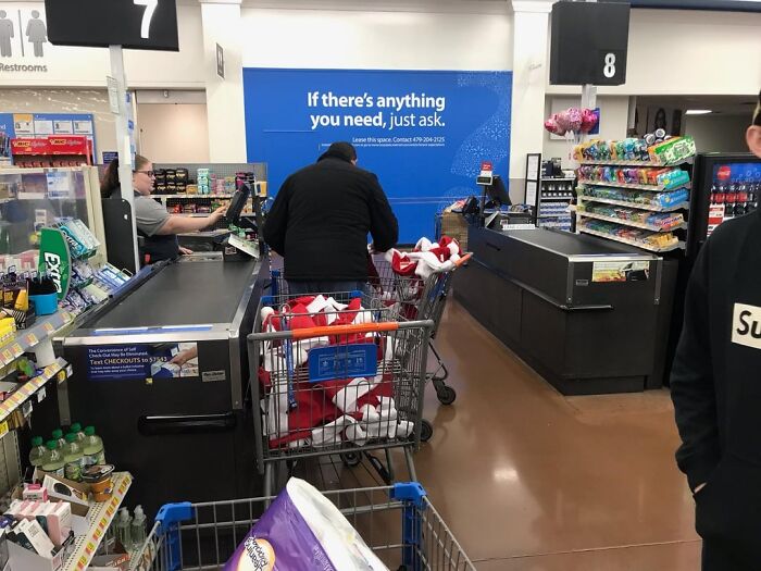 Person shopping with full cart at grocery store checkout in a community support setting