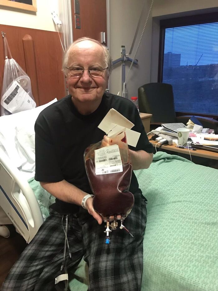 Smiling elderly man in hospital holding a bag of donated blood