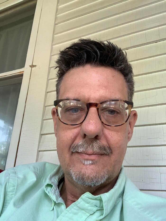 Selfie of a man with glasses sitting on a porch