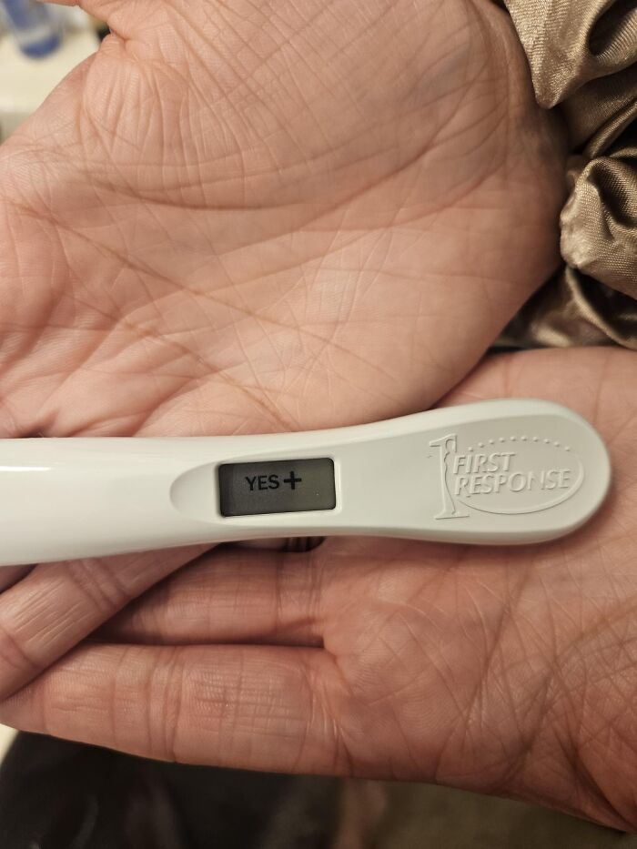 Positive digital pregnancy test in hand showing a yes plus result