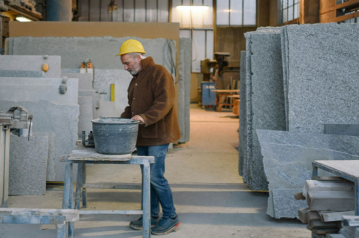 Worker in hard hat handling materials in stone fabrication career