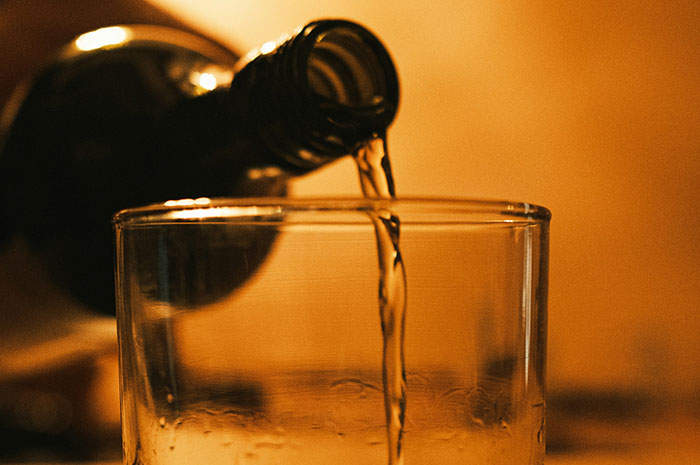Pouring alcohol into a glass illustrating risks in beverage-related careers