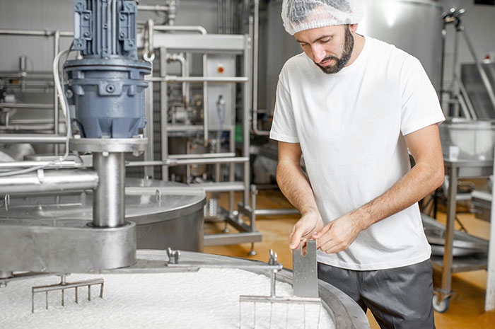 Worker overseeing industrial food manufacturing process in career setting