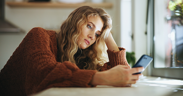 Woman looking upset and distracted while checking her phone amid family feud