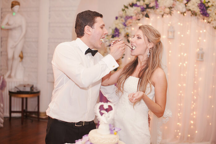 A smiling bride and groom feeding each other cake at their wedding, symbolizing love and commitment, among weddings that went off the rails.