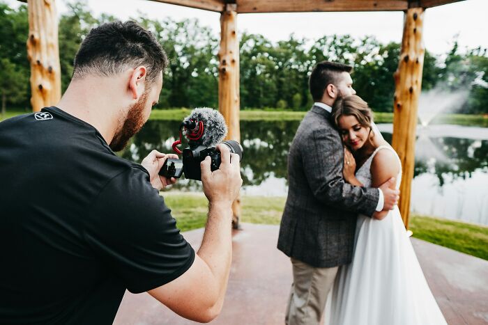 A photographer capturing a wedding couple embracing by a lake. Many weddings go off the rails, but this one looks serene.