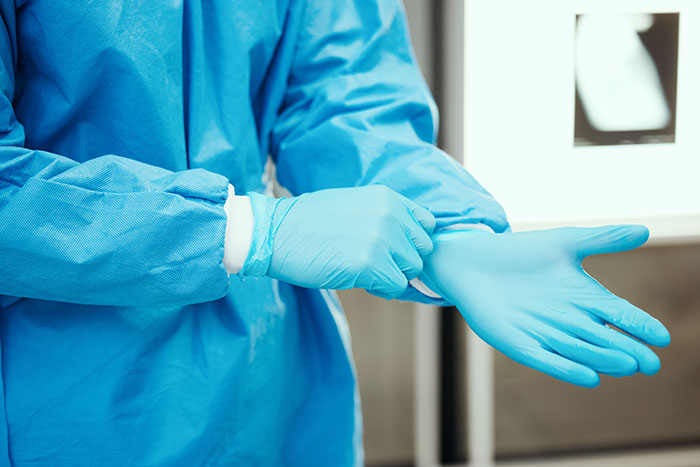 Person wearing blue medical gloves preparing for exam Person wearing blue medical gloves preparing for exam