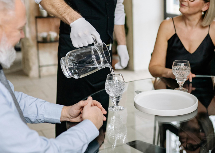Waiter pouring tap water into glass at Italian hotel restaurant Waiter pouring tap water into glass at Italian hotel restaurant