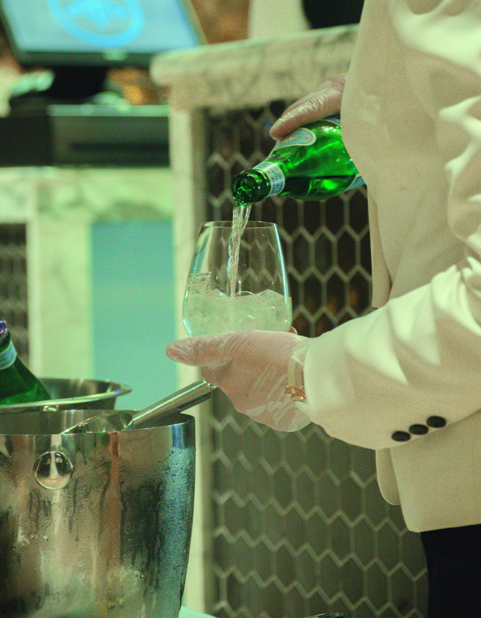 Hotel staff pouring mineral water into glass with ice Hotel staff pouring mineral water into glass with ice