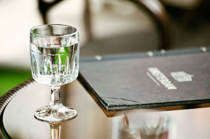 Glass of tap water on table next to hotel menu Glass of tap water on table next to hotel menu