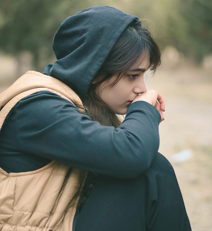 Thoughtful young woman wearing hoodie sitting outdoors Thoughtful young woman wearing hoodie sitting outdoors