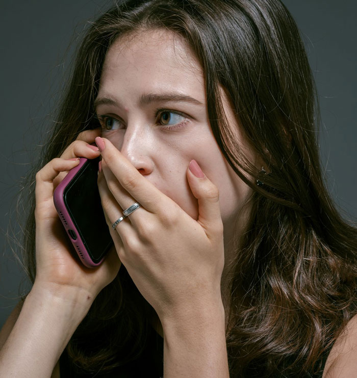 Worried woman covering mouth while talking on phone Worried woman covering mouth while talking on phone