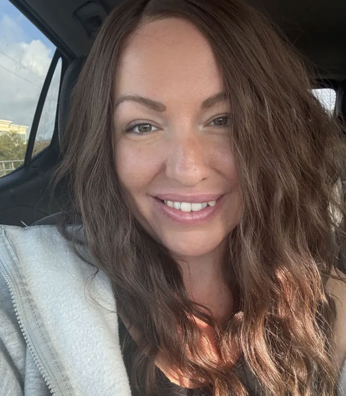 Close-up of woman smiling inside a car with wavy brown hair