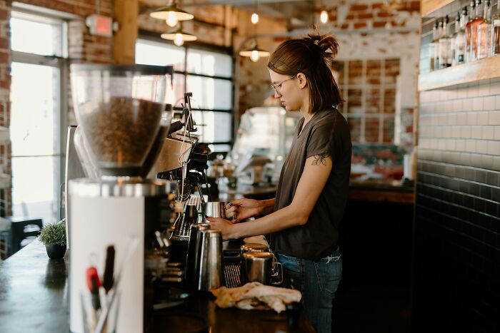 Woman working as a barista making coffee in a rustic cafe