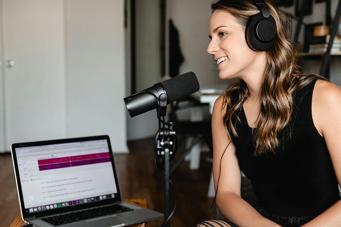 Woman recording podcast with microphone and laptop
