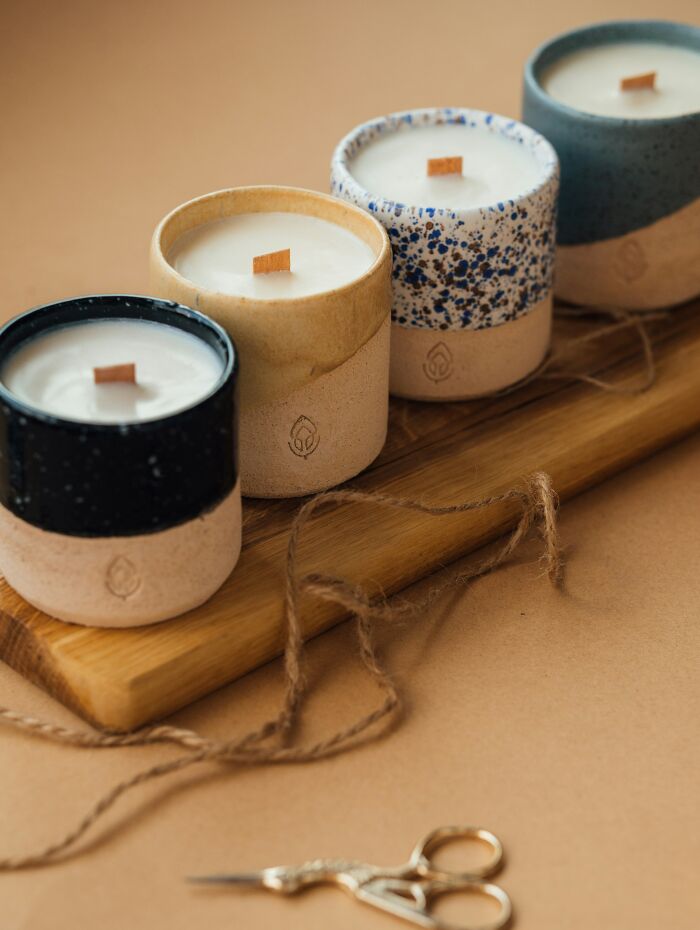 Handmade candles in ceramic holders on wooden board