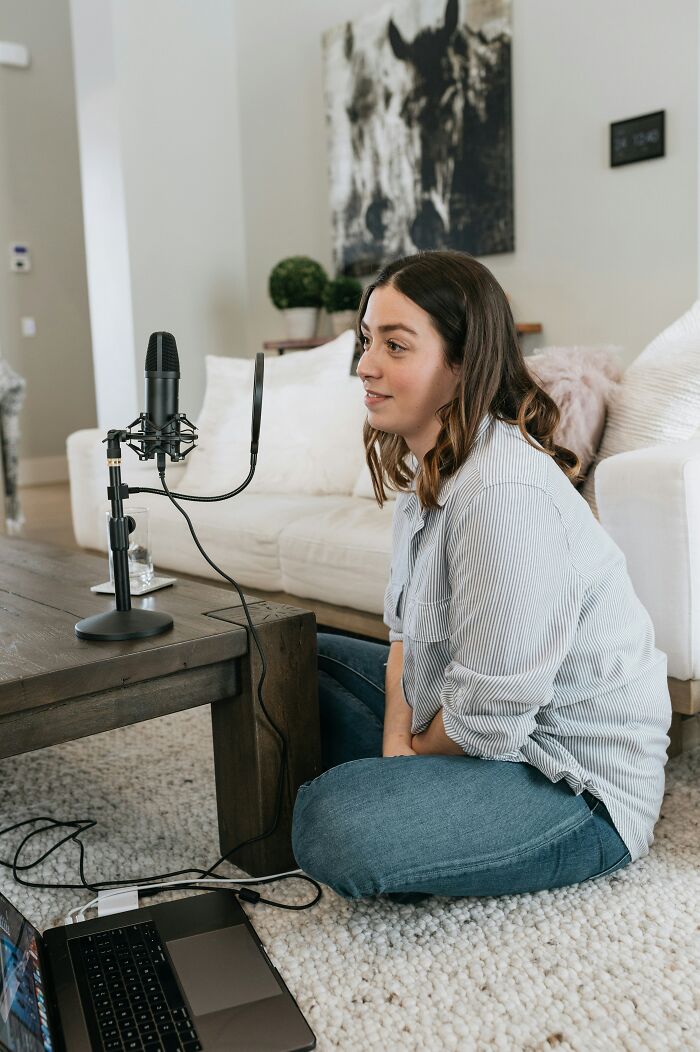 Woman recording podcast at home with microphone and laptop