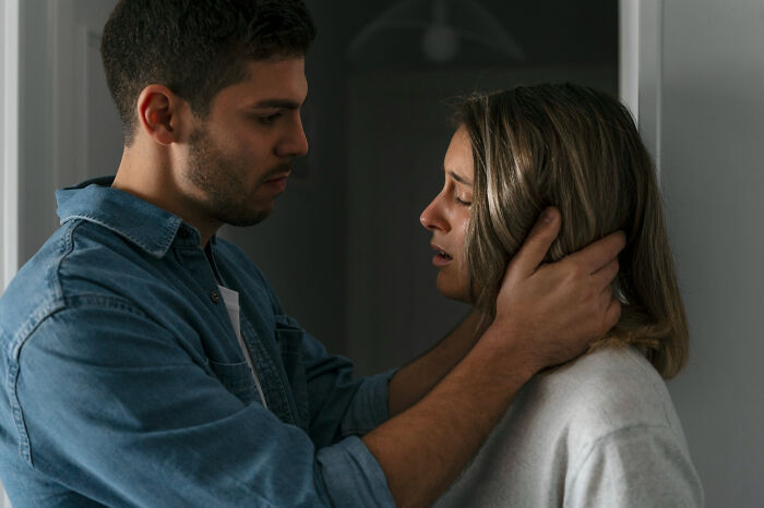 A man in a denim shirt holds a crying woman's face, depicting the emotional pain of breakups. Heartbroken people share their stories.