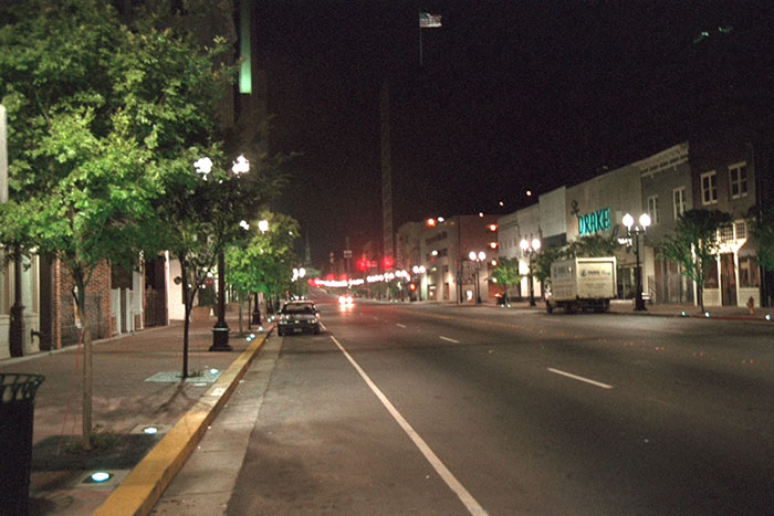 Empty downtown street at night with street lights and few vehicles