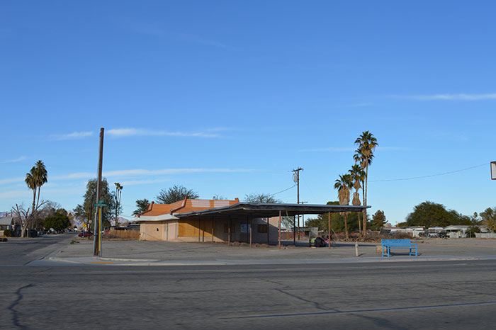 Vacant commercial building surrounded by palm trees on an empty street