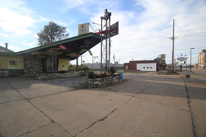 Abandoned gas station with cracked pavement and empty lot in US city