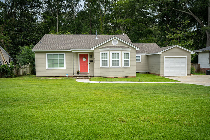 Suburban house with green lawn and red front door in the US