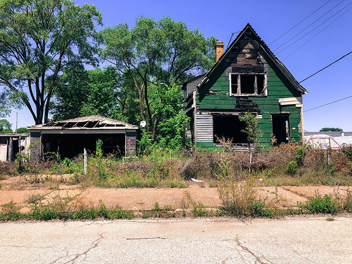Abandoned burnt green house with overgrown yard in the US
