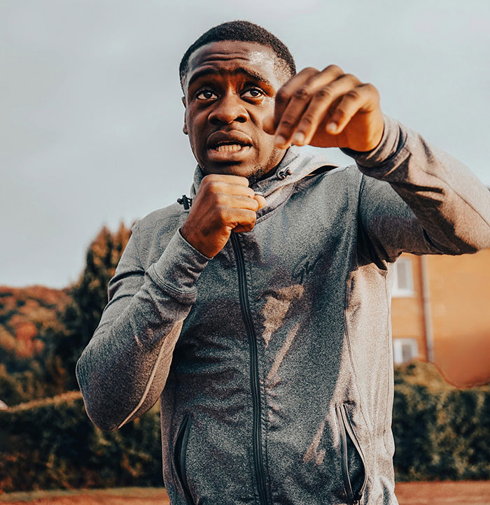 Man in a gray hoodie with clenched fists, appearing ready to fight. Depicts road rage is no joke.