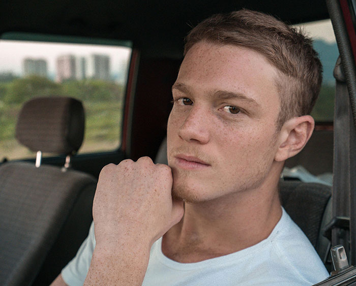 A serious young man with freckles in a car, contemplating the issue of road rage and drivers losing their minds.