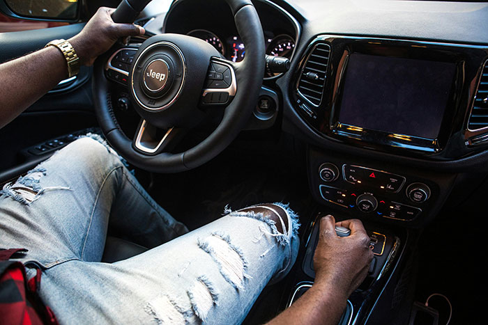 A driver's hands on the wheel and gear shift of a Jeep, showcasing a moment of concentration, relatable to road rage.