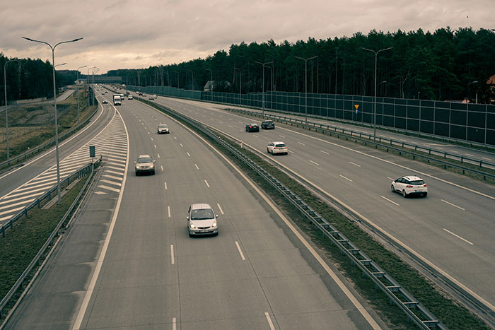 Cars on a multi-lane highway, with forest and sound barriers in the background, a common scene where road rage can ignite.