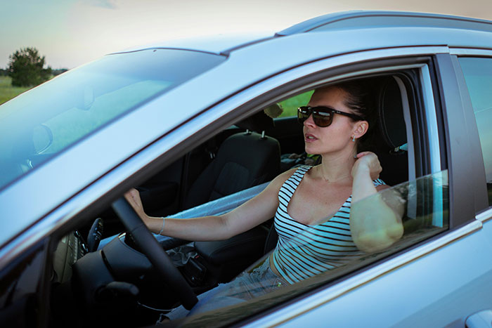 A woman in sunglasses and a striped top looks out of a car window, showing a moment from drivers completely lost their minds.