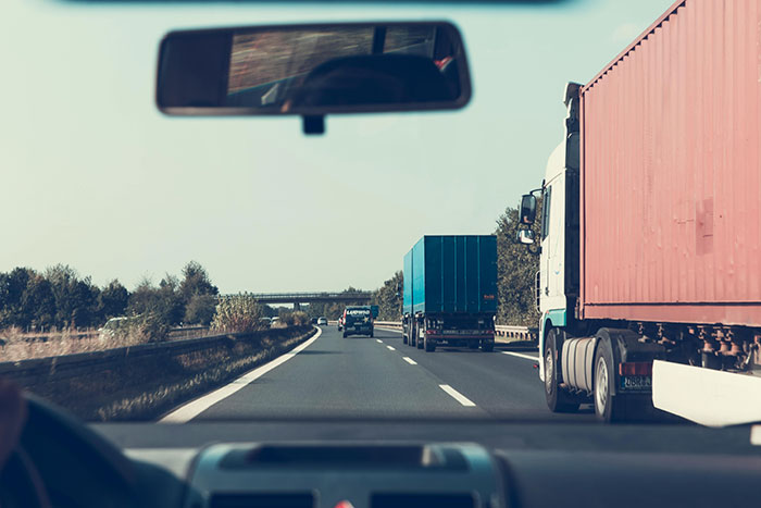 A driver's view from a car on a highway, with multiple trucks and cars visible, highlighting road rage concerns.