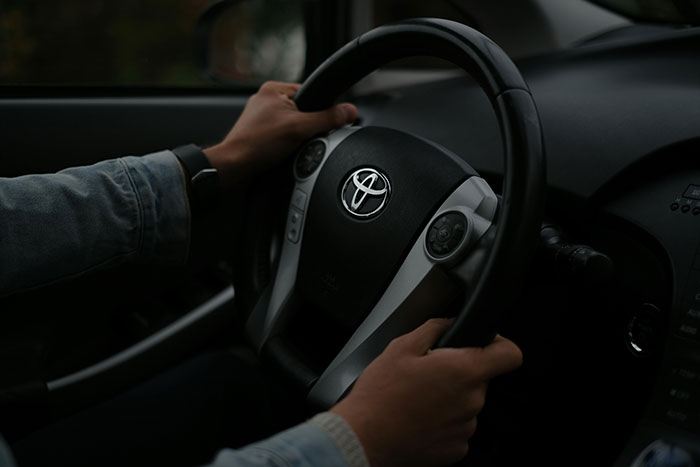 Hands grip a Toyota steering wheel. Road rage can manifest, showing drivers completely losing their minds on the road.